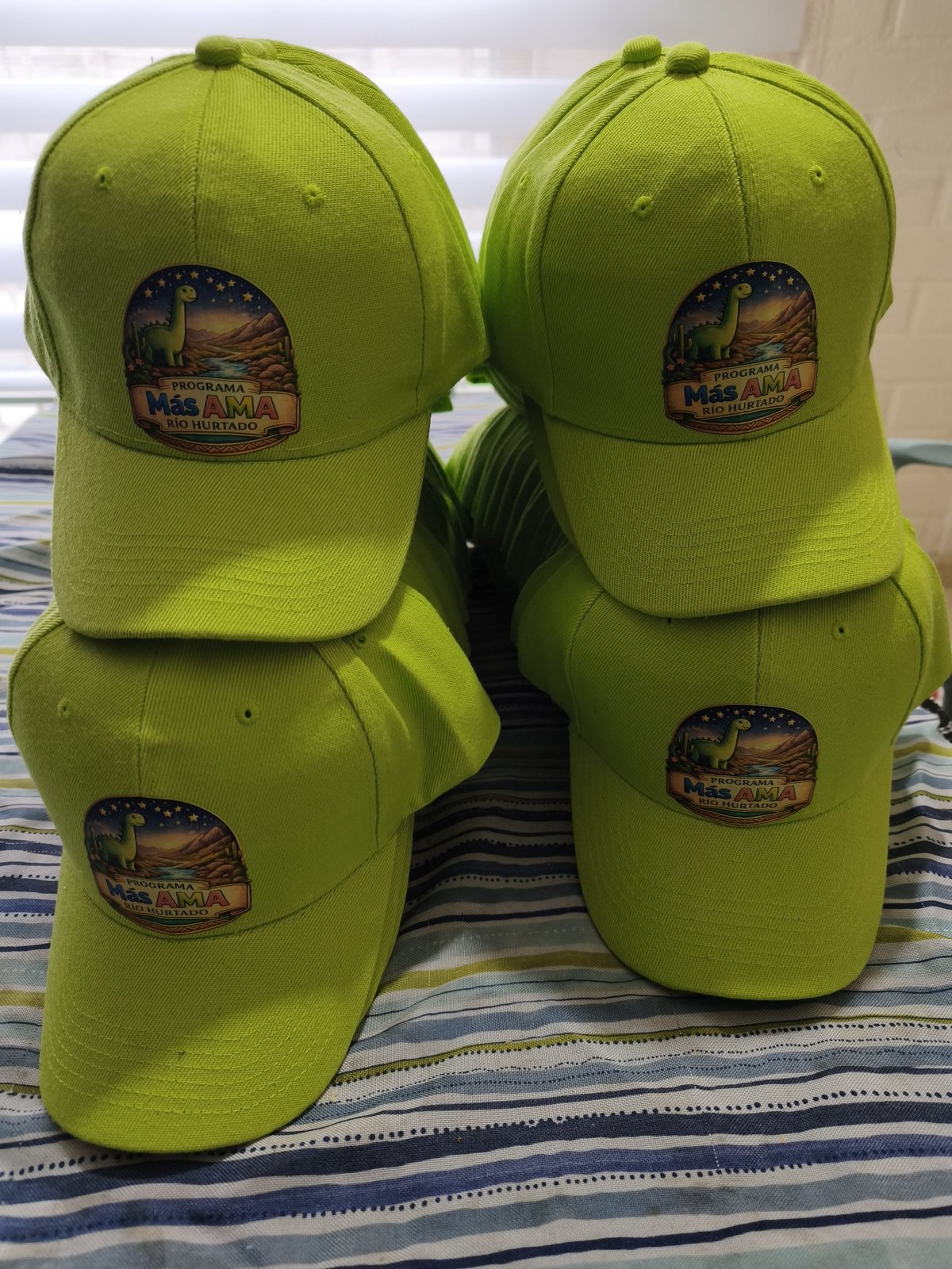 Gorras verdes con logo del Programa Más AMA